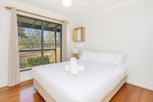 a white bedroom with a bed and a window at Shiraz Vineyard Estate in Pokolbin +18 photos