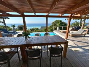 a wooden table and chairs on a deck with the ocean at Makana 3A in Ponta Mamoli