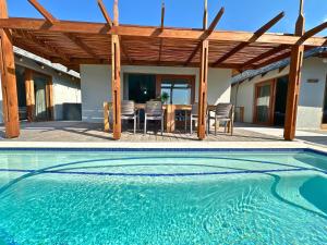a swimming pool in front of a house with a table and chairs at Makana 3A in Ponta Mamoli
