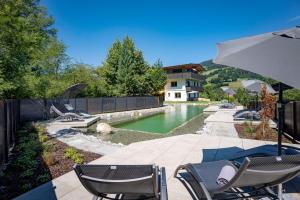 a patio with chairs and an umbrella next to a pool at Appartements Andrea Cäciel - Alpline Appartements KG in Brixen im Thale