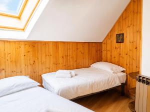 two beds in a room with wood paneling at Appartamento Lisander in Ponte di Legno