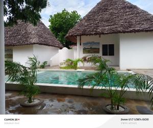 a villa with a swimming pool and two buildings at Tranquil villa in Watamu