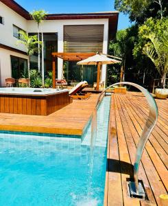 a swimming pool with a hot tub and a wooden deck at Green House Praia do Forte- 4 Suítes Premium in Mata de Sao Joao