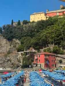 a beach with blue umbrellas and a red building at Benvenuto Beach House in Monterosso al Mare