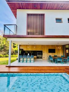 a house with a swimming pool in front of a house at Green House Praia do Forte- 4 Suítes Premium in Mata de Sao Joao