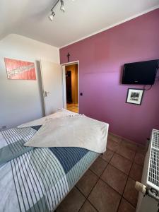 a bedroom with purple walls and a bed with a flat screen tv at Oase für Reisende & Geschäftsleute in Meerbusch