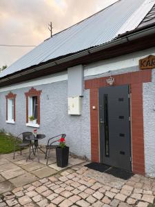 a white building with a black door and a table at Chata na Karpackiej in Kostrzyca