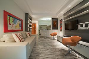 a living room with a couch and a tv at Hotel Sequoia Alphaville in Barueri