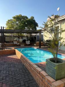 a swimming pool in a brick wall next to a house at TLMZ Guesthouse in Newcastle