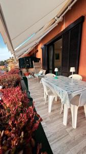 a patio with white tables and chairs and flowers at argentario home in Porto Santo Stefano