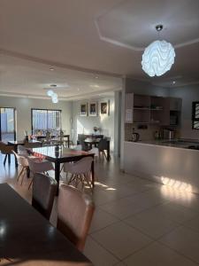 a kitchen and dining room with tables and chairs at TLMZ Guesthouse in Newcastle