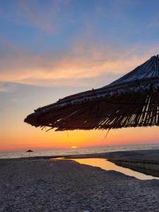 an umbrella on the beach with the sunset in the background at Erna Apartment in Golem
