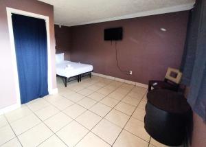 a room with a bed and a chair and a tv at Sunset Motel in Las Vegas