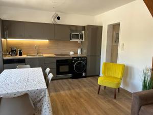 a kitchen with a table and a yellow chair at Casa Parcului in Villers-sur-Mer
