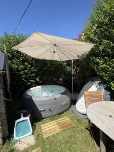 a hot tub and an umbrella next to a table at la bulle d'Astrée in Le Tronchet