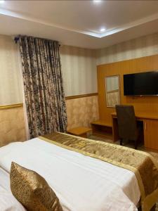 a hotel room with a bed and a desk and a television at Goldstep Hotel Asaba in Asaba