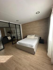 a bedroom with a white bed and a mirror at Urban Loft Rosal - parking privado in Oviedo