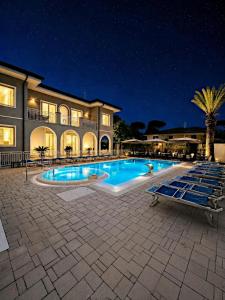 a swimming pool in front of a house at night at Hotel Fortunella in Lido di Camaiore