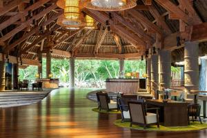 a lobby with wooden ceilings and tables and chairs at Le Domaine Deva, Series by Marriott in Bourail