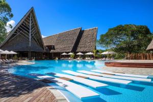 a swimming pool with lounge chairs in front of a building at Le Domaine Deva, Series by Marriott in Bourail
