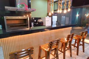 a restaurant with a bar with four wooden chairs at Quinta Heluue in Ciudad del Este