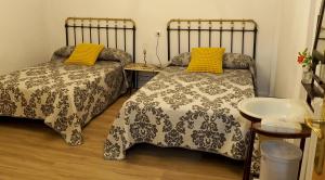 a bedroom with two beds with yellow pillows and a sink at Casa Rural Lutia in Andaluz