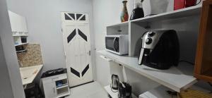 a kitchen with a white door and a microwave at Studio Cinza em frente à praia in Aracaju