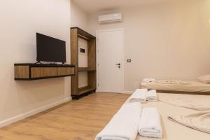 a room with two beds and a flat screen tv at Ambra & Arber Hotel in Bogovë