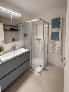 a white bathroom with a shower and a sink at Vila Ester - apartman Lovrana in Lovran