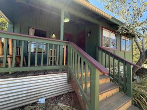 a green house with a wooden staircase leading to the front porch at Priest Station Cafe & Cabins in Groveland