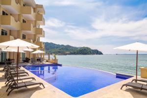a hotel swimming pool with chairs and umbrellas at Hotel Bogavante in Barra de Navidad