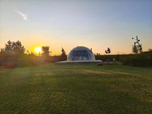 a greenhouse in a field with the sunset in the background at Domein de Koekoeksvlooghe in Lo-Reninge