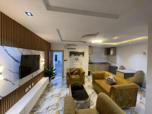 a living room with couches and a flat screen tv at Oak Haven Lodging & Suites in Sagamu