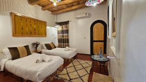 a room with two beds and a table in it at Hotel Atlas Gorge Dades in Boumalne Dades