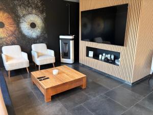 a living room with a table and two chairs and a television at Maison des W in Jalhay