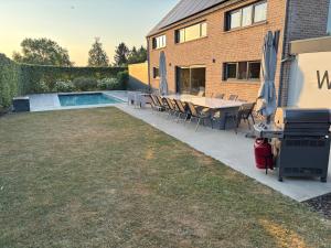 a backyard with a table and chairs and a pool at Maison des W in Jalhay