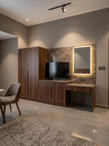 a living room with a tv and a chair and a mirror at Hotel Sakthi-Pallava Shore's in Mahabalipuram