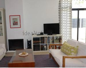 a living room with a white couch and a tv at Preciosa duplex en el Rompido in El Rompido