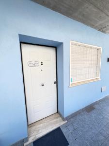 a white door in a blue wall with a window at Bassa Marea in Nettuno