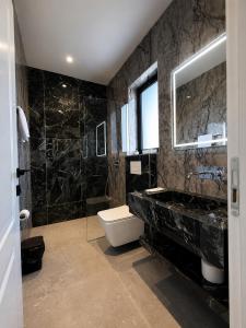 ein Badezimmer mit Toilette, Waschbecken und Spiegel in der Unterkunft Hotel Muja in Rinas