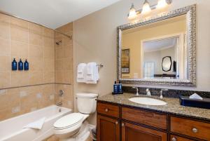 a bathroom with a toilet and a sink and a mirror at WorldMark Reunion in Kissimmee +21 photos