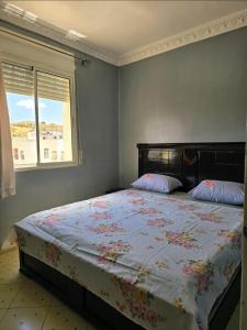 a bedroom with a bed with a floral bedspread and a window at Morjan apart in Tangier +17 photos