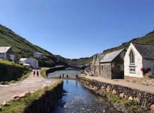 a body of water next to a river with buildings at Boscastle Bell Tents in Boscastle