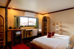 a bedroom with a bed and a desk and a window at Palmcove Chiang Mai Old Town in Chiang Mai