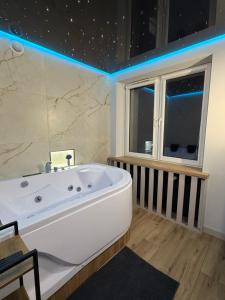 a bathroom with a white tub and a window at MAX Apartaments in Częstochowa +9 photos