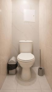 a white bathroom with a toilet and a trash can at Золотые пески in Bosteri