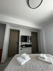 a white bedroom with two towels on a bed at Tsonas Maisonette in Lygia +9 photos