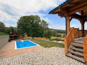 a backyard with a swimming pool and a wooden deck at Srub Chodov in Chodov