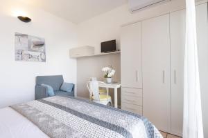 a white bedroom with a bed and a desk at Studio 2- lake view in Oggebbio
