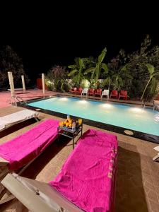 a swimming pool with pink blankets and chairs next to it at Riad Belgika Marrakech in Ourika